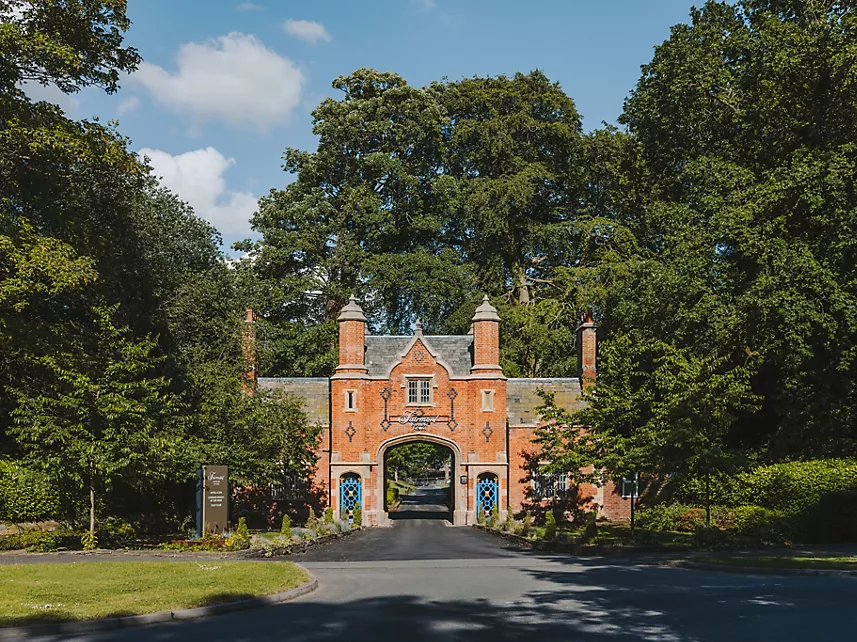 The red-brick gatehouse at Fairmont Cheshire, The Mere – a tree-lined entrance to the countryside hotel and event venue