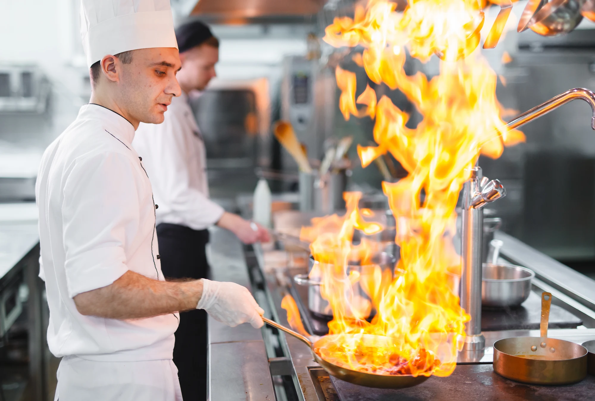 A Foodlink chef flambéing a pan in a professional kitchen