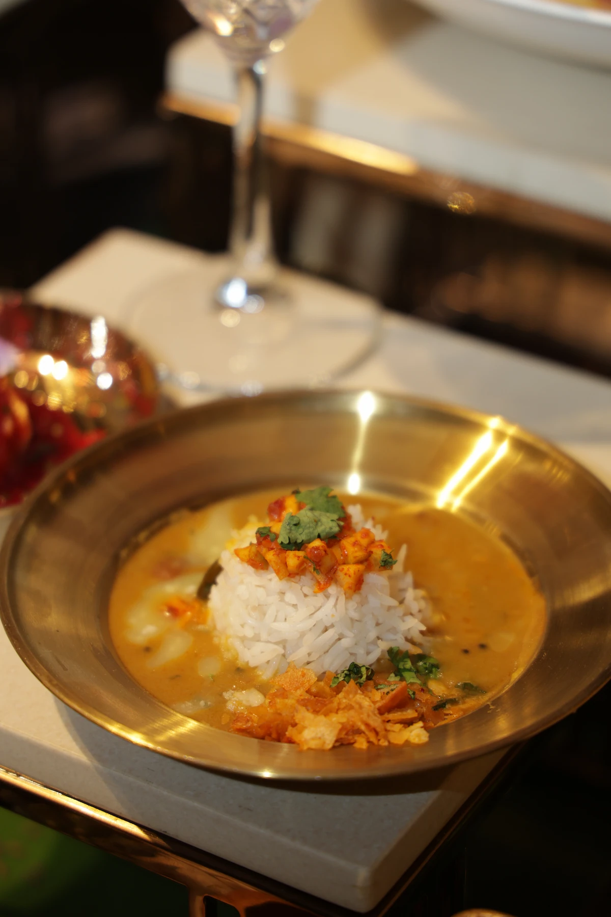 A plated rice dish with garnish in a gold-rimmed bowl, lit by candlelight