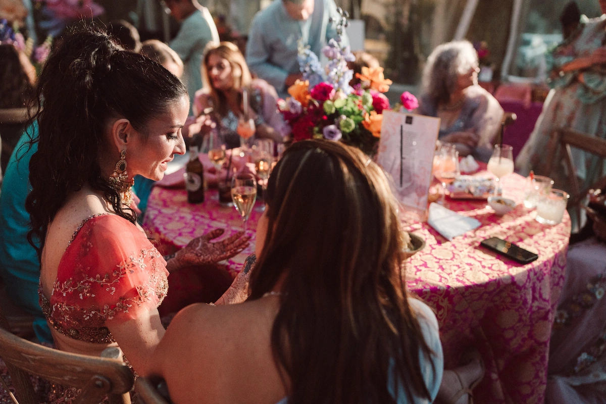 Guests seated at a candlelit dinner table decorated with flowers