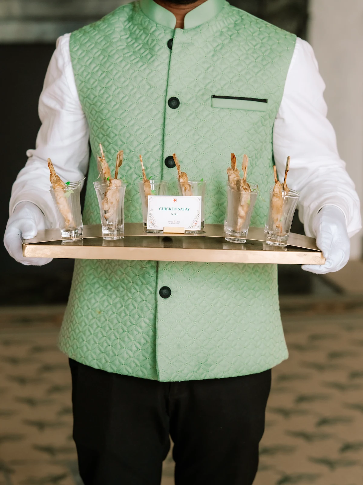 A waiter in white gloves carrying a tray of canapés