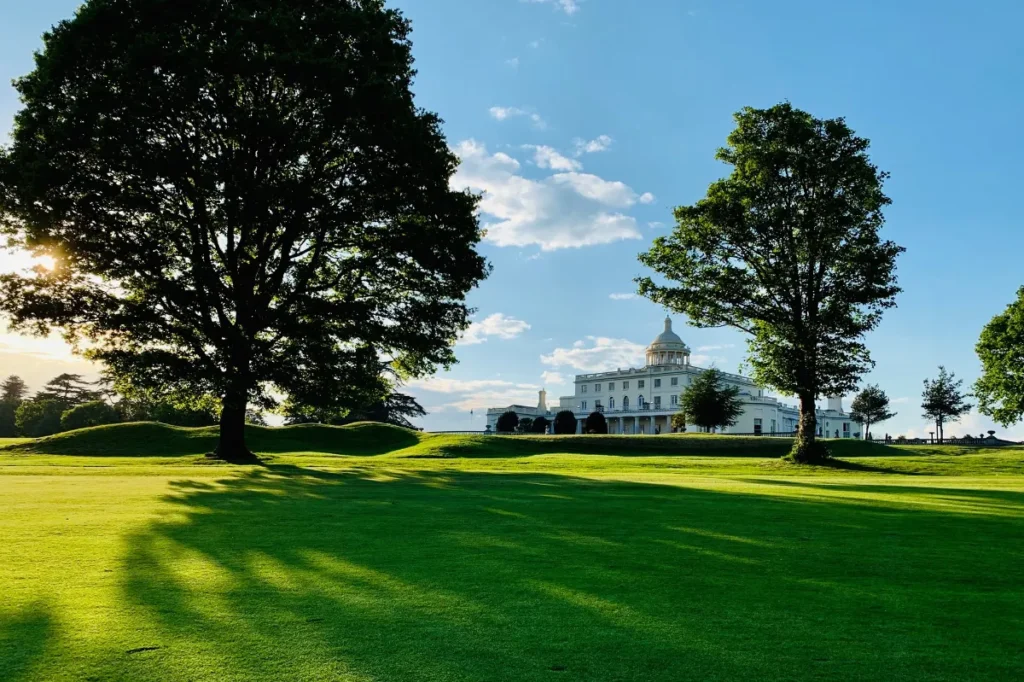 Stoke Park's Palladian mansion seen across sunlit parkland in Buckinghamshire, a country estate event venue